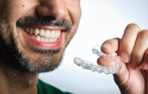 dark-haired man with beard putting on transparent dental retainer