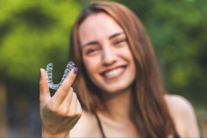 beautiful smiling turkish woman is holding an invisalign bracer with vibrant colours